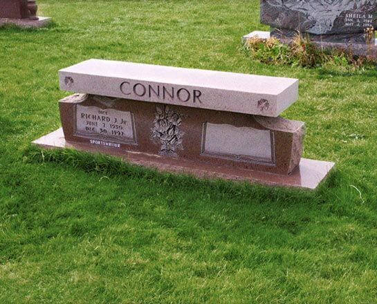 Rose granite memorial bench with a carved floral panel