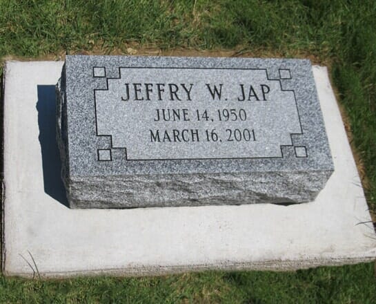 Grey granite bevel marker with a lined border, set on a concrete foundation