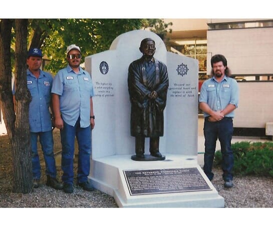 Three Norman's Memorials crew members standing beside a finished memorial with a bronze figure at its centre