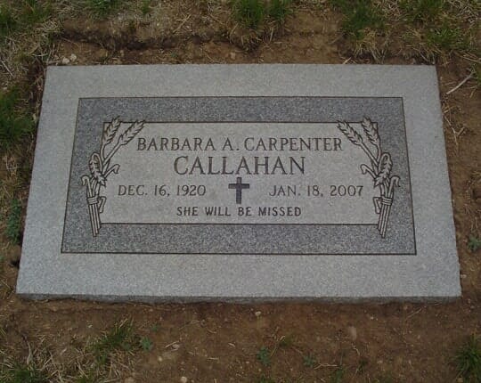Flush grey granite marker with carved wheat sheaves and a cross