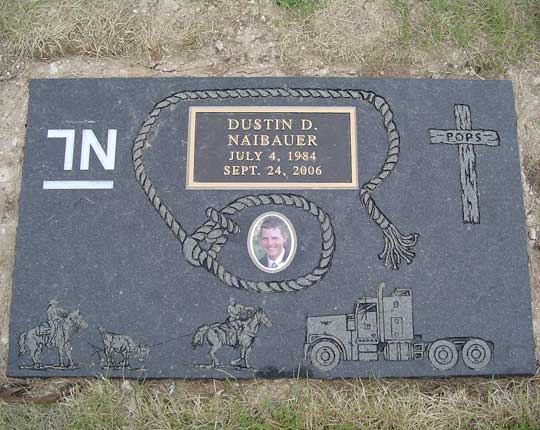 Dark granite flat marker with a bronze plate, a carved rope border, horses and a truck