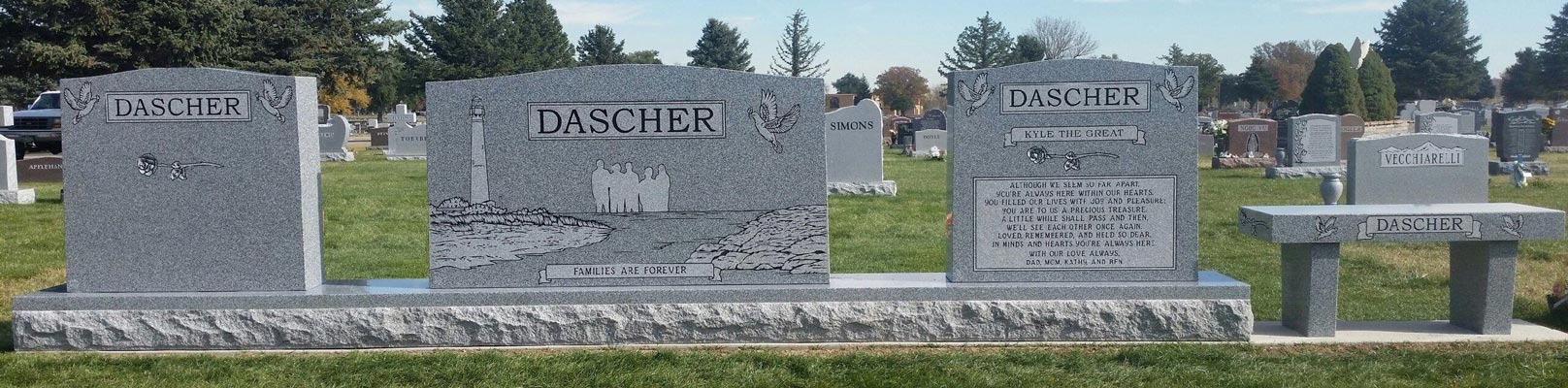 A full family memorial set of two uprights, a centre stone with an etched lighthouse and a matching granite bench, standing in a Colorado cemetery