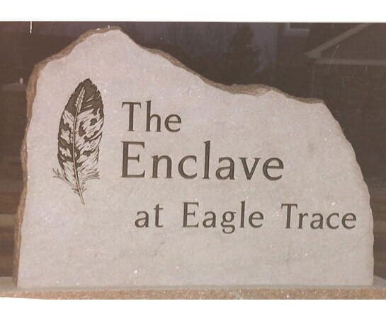 A natural edged sandstone entrance sign with a carved feather
