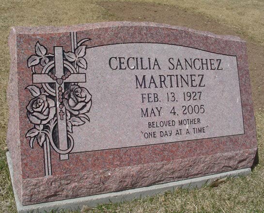 Rose granite slant marker with a carved cross, rosary and roses