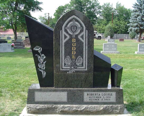 Black granite upright carved with a stained glass style cross and doves, with black wings either side